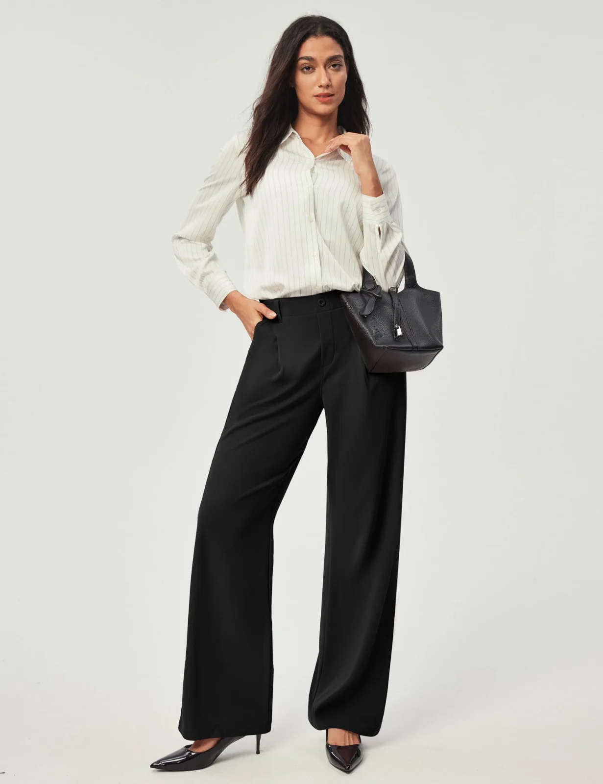 The wide-leg dress pants in black with a white shirt and a bag, walking