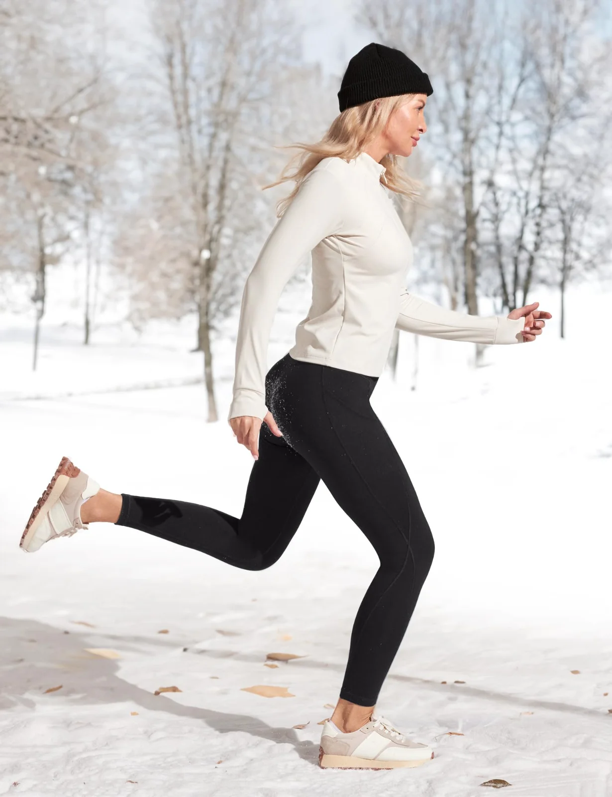 The fleece-lined leggings in black on a run through a snowy park, in a beanie